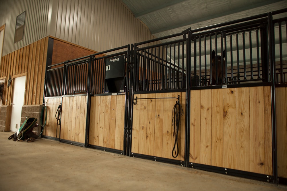 Horse stalls with treated wood and metal grills inside a Florida pole barn by Nelson’s Metals